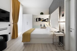 Una camera d'albergo moderna con un letto, un comodino e una TV a parete.