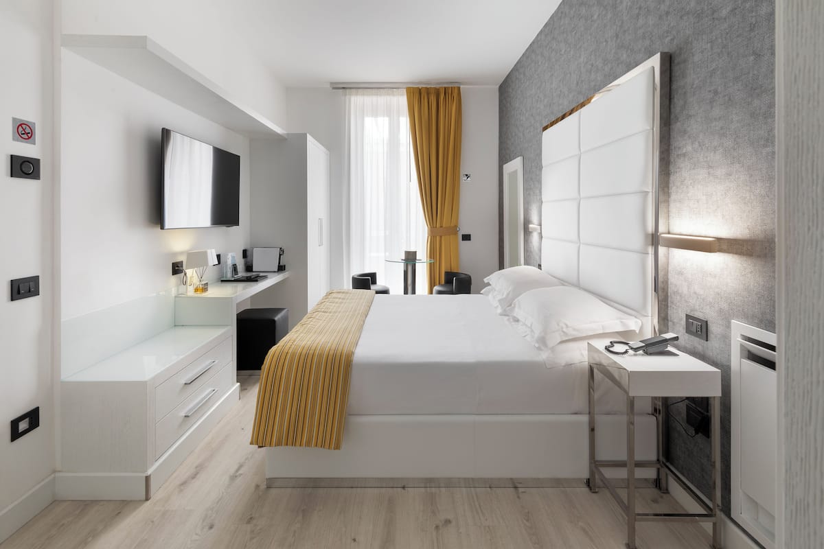 A modern bedroom with a bed, bedside table, and a TV mounted on the wall.