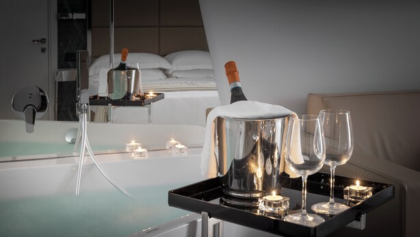 Un mini-bar comprenant une bouteille de champagne, des verres et des bougies, le tout disposé sur un plateau.