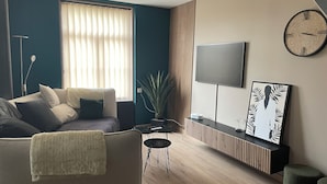A modern living room with a sofa, a coffee table, a TV mounted on the wall, and a framed artwork.