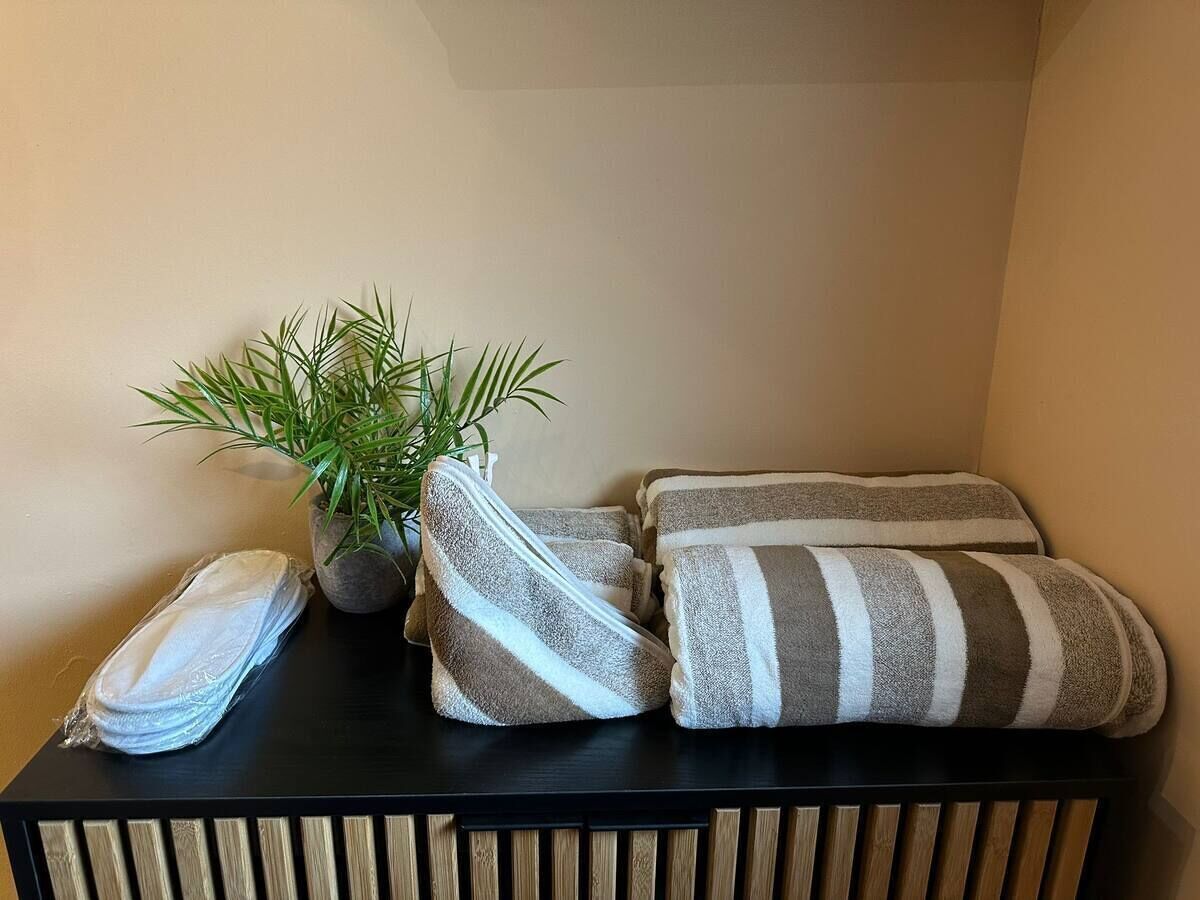 Un coin de pièce avec une table noire, une plante en pot et des serviettes à rayures.
