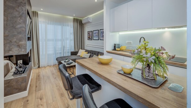 A modern living room with a sofa, a dining table, and a kitchen area with a countertop and a sink. - Romanca Deluxe Studio - City View (Split)