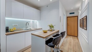 A modern kitchen with white cabinets, a wooden countertop, and a small island with a sink and a yellow bowl. - Romanca Deluxe Studio - City View (Split)