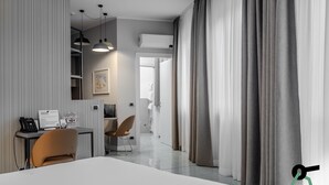 Una habitación de hotel moderna con una cama grande, un escritorio con teléfono, una silla y un cuadro en la pared.