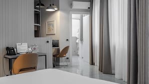 A modern hotel room with a large bed, a desk with a chair, a small table with a chair, a telephone, and a framed picture on the wall. - Hotiday Apartments La Spezia (La Spezia)