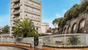 A multi-story building with balconies, a palm tree, and a stone wall with arches. - Hotiday Apartments La Spezia (La Spezia)