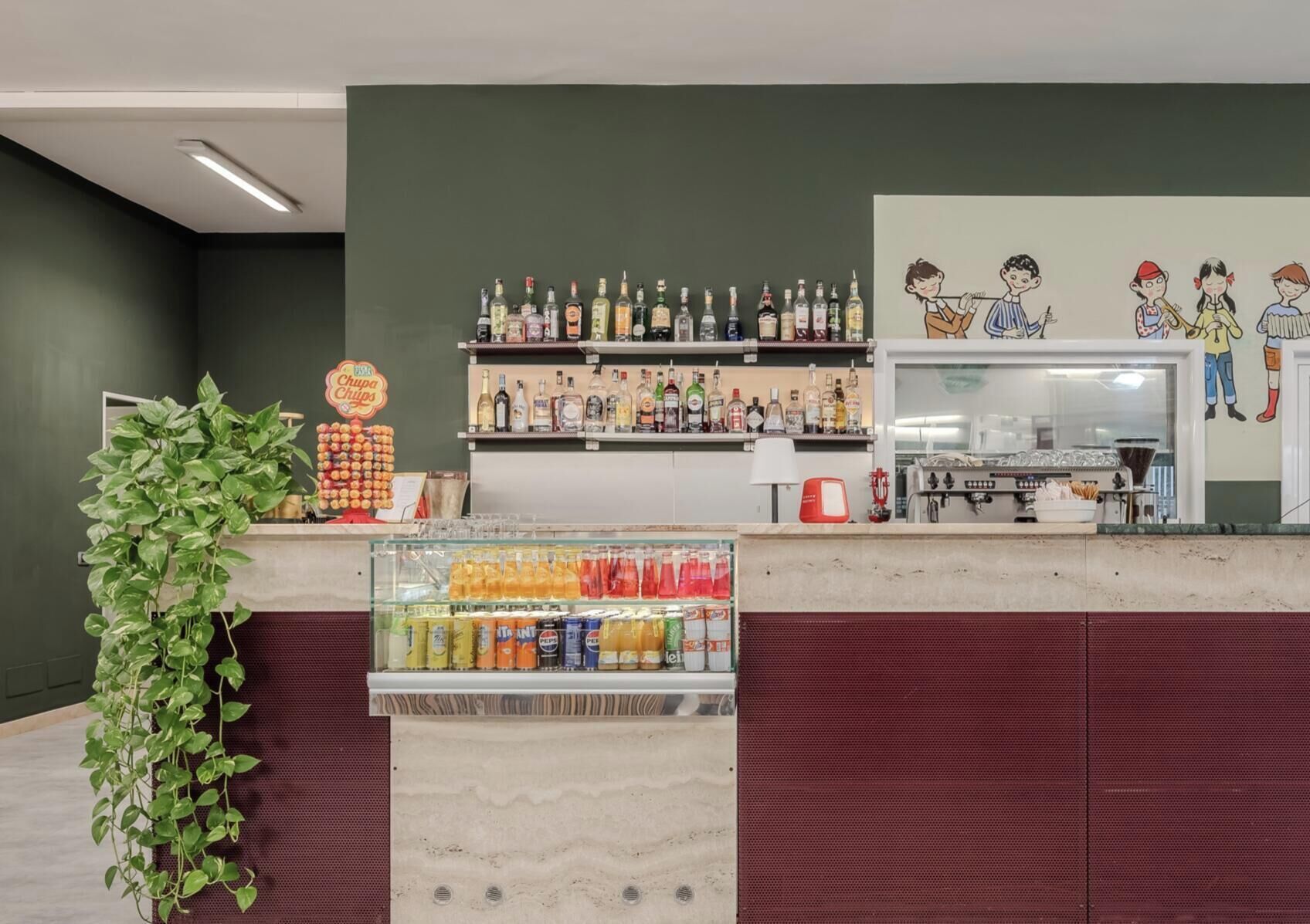 A bar area with a variety of beverages, a snack display, and a mural of children.