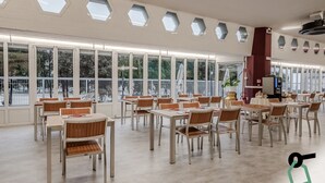 Un amplio comedor interior con ventanas hexagonales, mesas y sillas de madera.