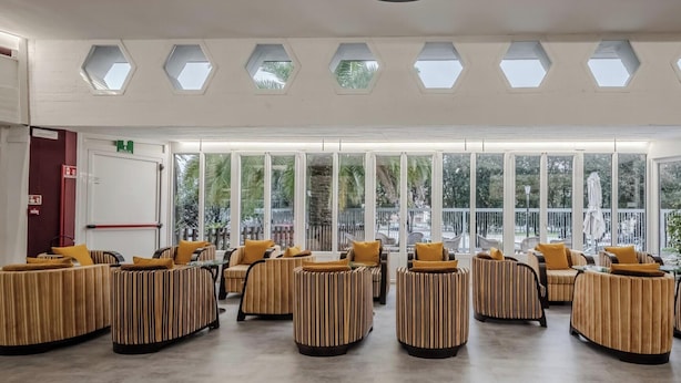A spacious indoor area with multiple seating arrangements and large windows providing natural light. - Hotiday Apartments La Spezia (La Spezia)