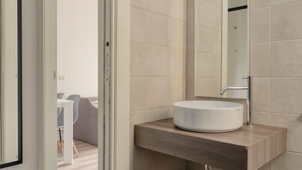 A modern bathroom with a round sink, a wooden countertop, and a large mirror.
