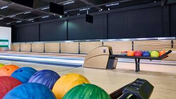 Une salle de bowling avec plusieurs pistes, un présentoir à boules de bowling et un éclairage au plafond.
