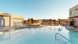 Una piscina con superficie de agua azul cristalina, rodeada de edificios modernos y palmeras.