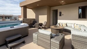 Una terraza en la azotea con un jacuzzi, mobiliario de mimbre y una pared de piedra.