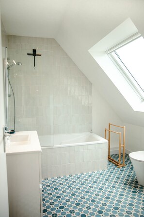 A modern bathroom with a skylight, a bathtub, and a shower.