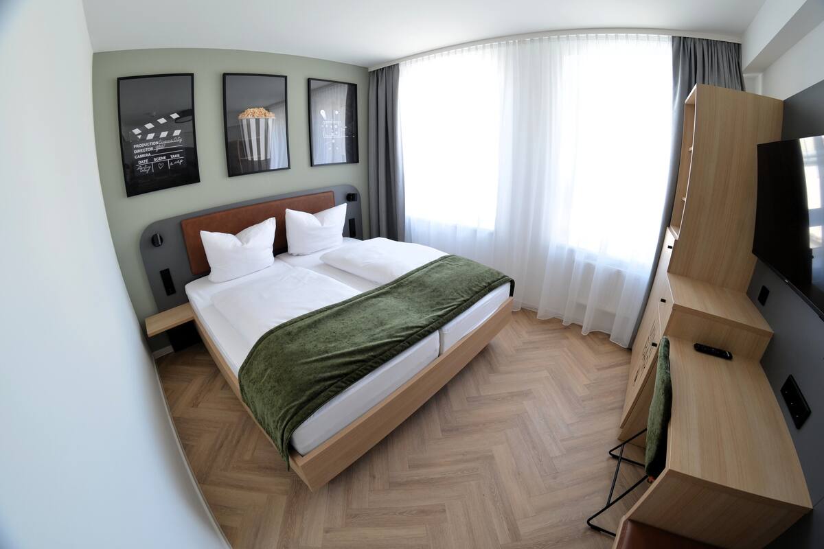 Une chambre d’hôtel avec un lit, une télévision et un bureau.