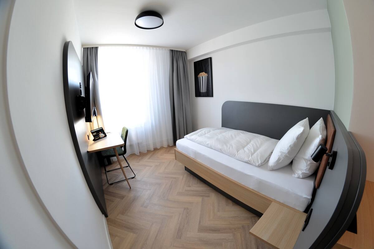Une chambre d’hôtel moderne équipée d’un lit, d’un bureau et d’une télévision.