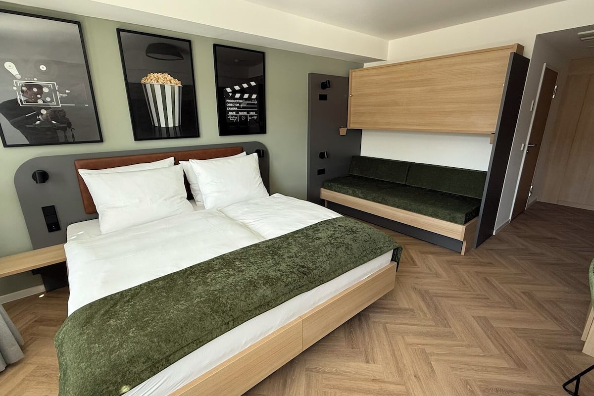 Une chambre d’hôtel moderne, équipée d’un lit, d’un banc et d’une armoire.