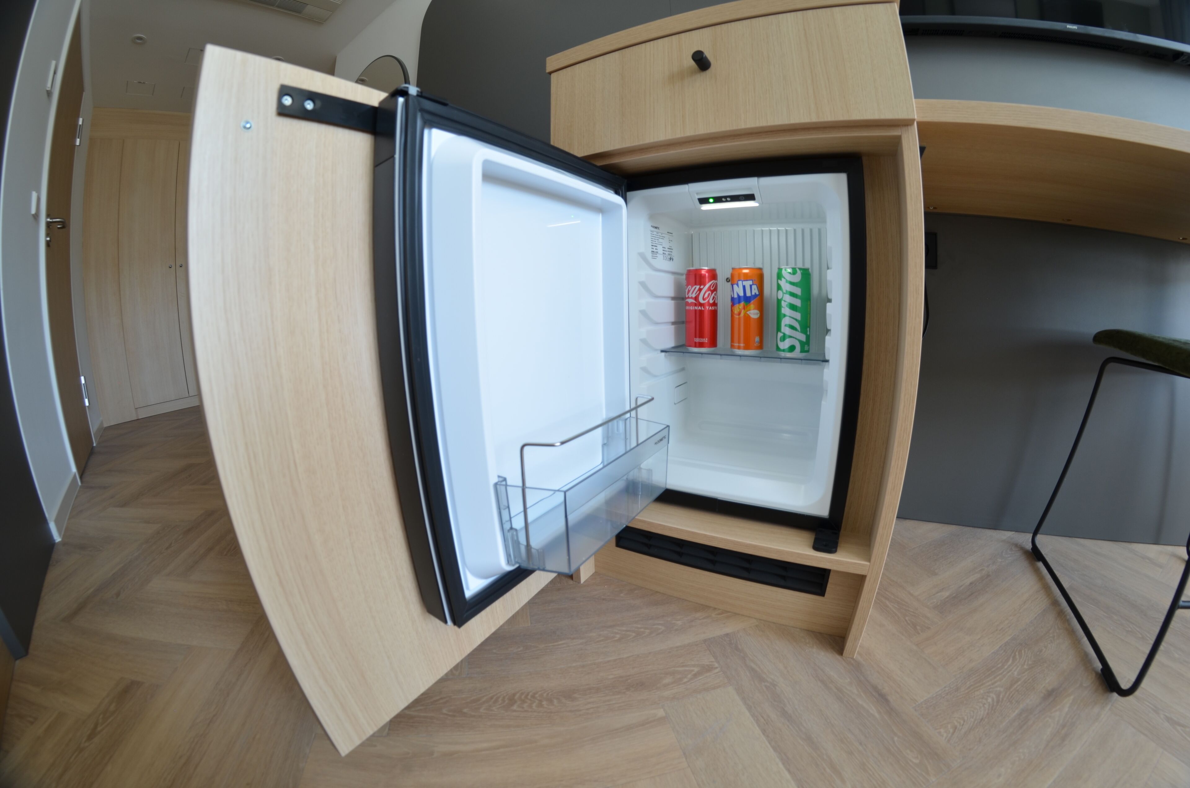A compact refrigerator with a transparent door, containing two cans of soda.