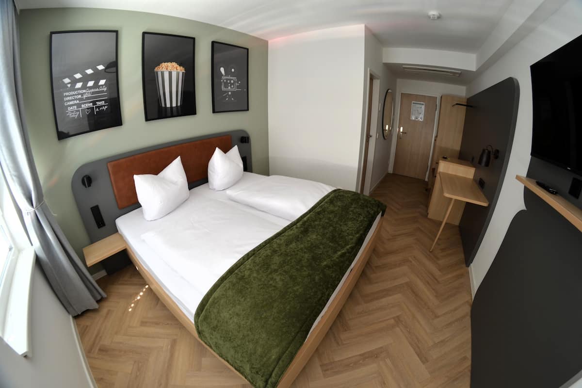 Une chambre d’hôtel moderne avec un grand lit, un bureau et une télévision.