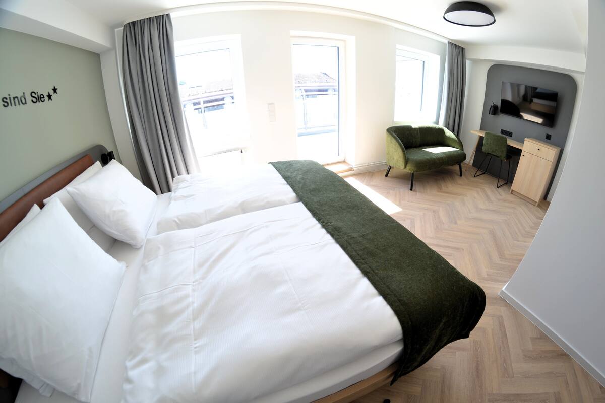 Une chambre d’hôtel avec un grand lit, un bureau, une chaise et un téléviseur.
