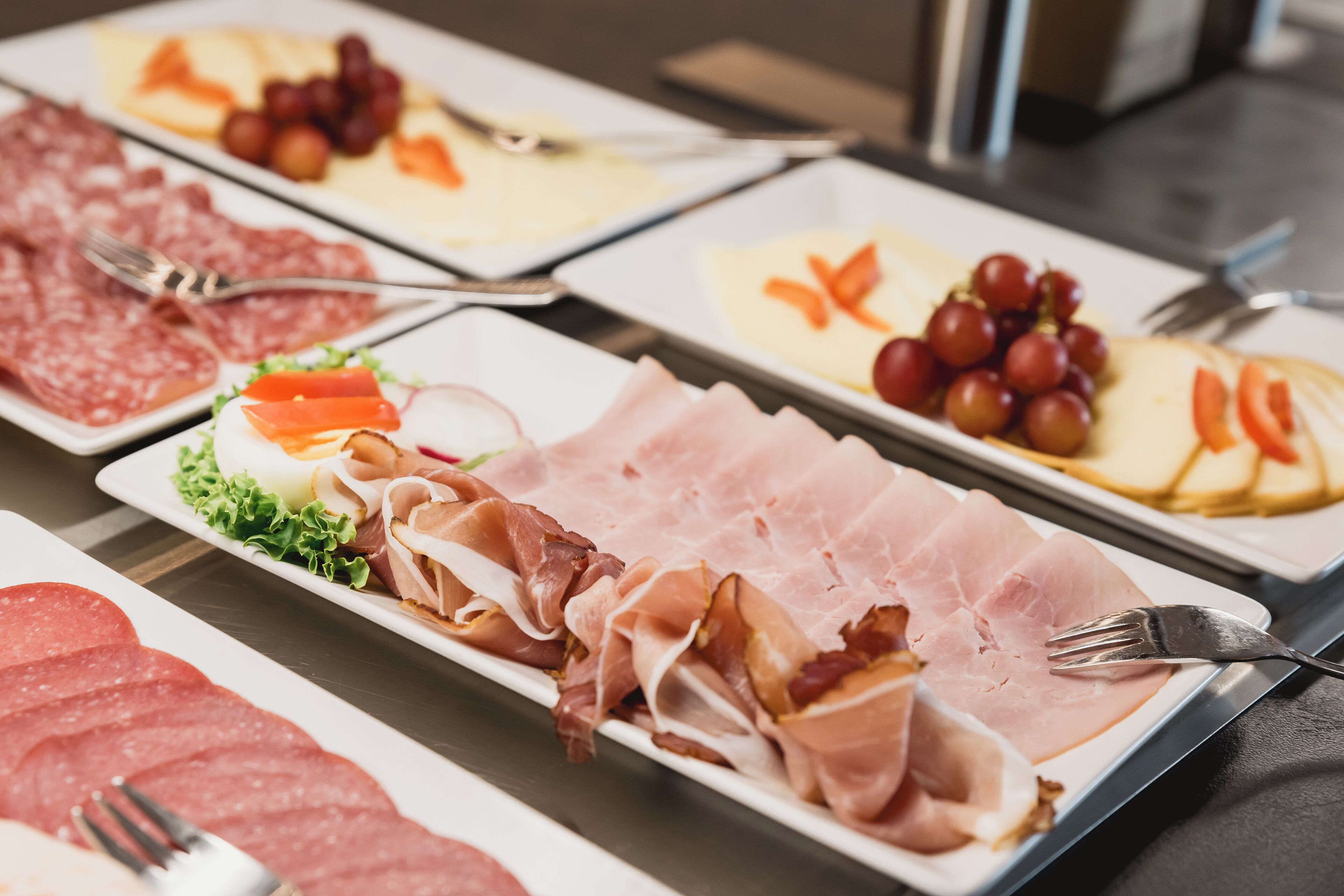 Un bufé con diversas opciones de comida, incluyendo carnes, quesos y frutas.
