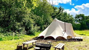 A camping site with a large tent, picnic tables, and a grill. - Little bridge Camp.
Secluded camping in 13 acres of magical meadow and woodland. (Hemyock)