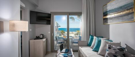A modern living room with a sofa, coffee table, and a view of the ocean through a sliding glass door.