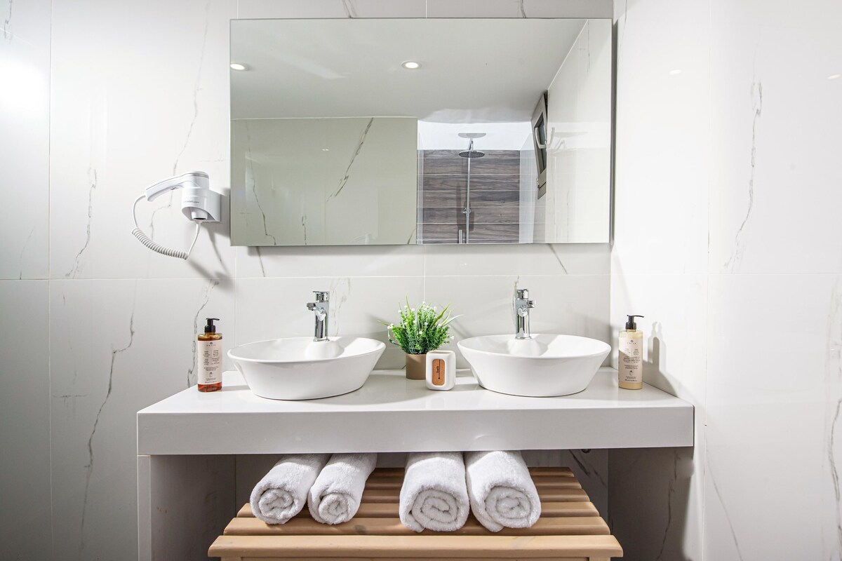 A bathroom with two sinks, a mirror, and a towel rack with towels.