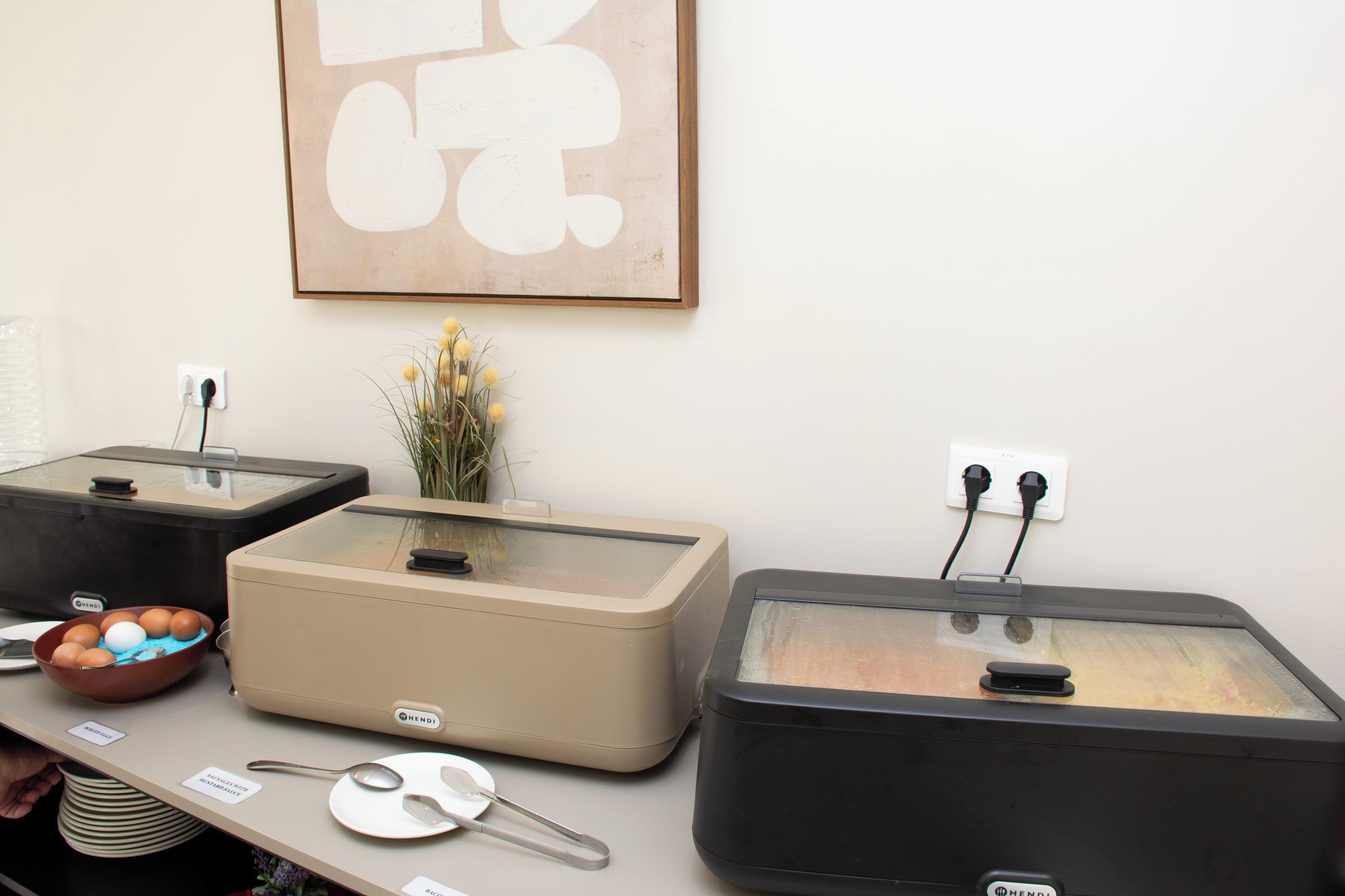 A kitchenette with a coffee maker, a blender, a food processor, and a bowl of fruit.