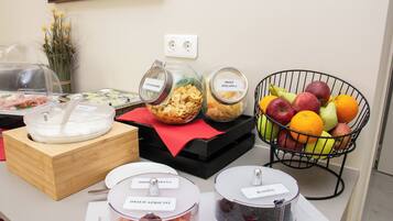 Buffet com diversas opções de comida e uma cesta de frutas.