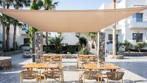 Une terrasse extérieure avec des tables et des chaises, entourée de murs en pierre et de palmiers.