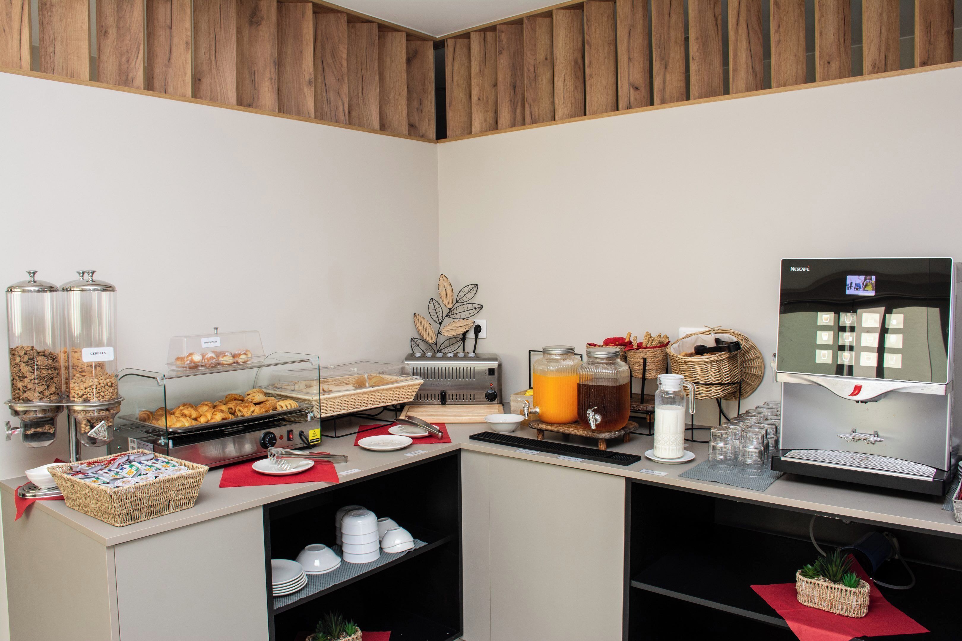 Een ontbijtbuffet met diverse etenswaren, een koffieapparaat en een sapautomaat.