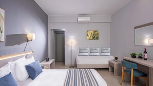 Une chambre d’hôtel moderne équipée de deux lits, d’un bureau, d’une chaise et d’une petite table agrémentée d’une plante et d’une bouteille.