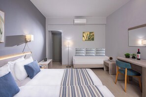 Een moderne hotelkamer met twee bedden, een bureau, een stoel en een klein tafeltje met een plant en een fles.