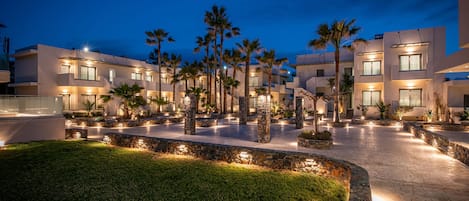 A modern hotel with multiple floors, outdoor palm trees, and a well-lit courtyard.