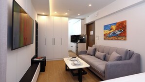 A modern hotel room with a sofa, a coffee table, and a TV mounted on the wall.