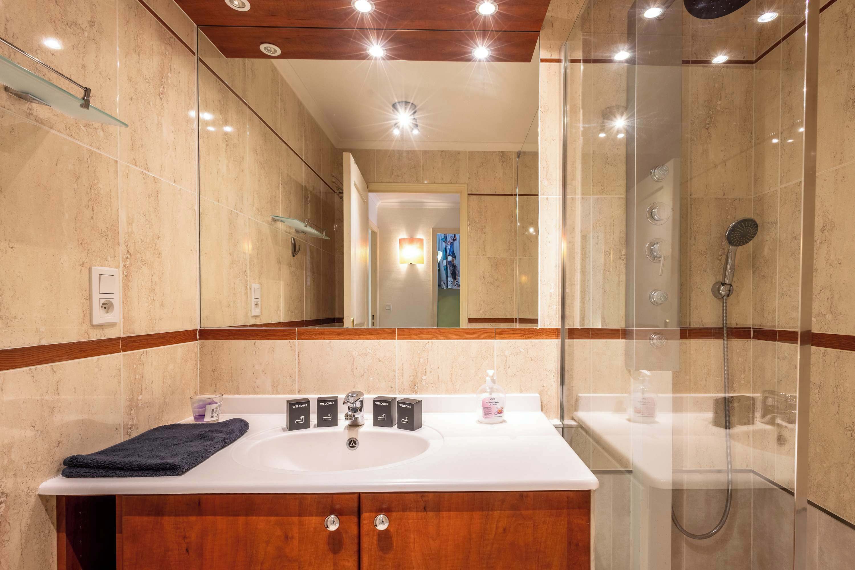 Een moderne badkamer met een ruime wastafel, een badmeubel en een douchecabine met glazen wanden.