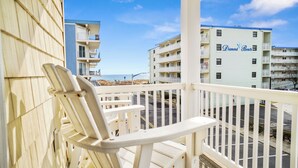 Ein Balkon mit weißen Stühlen mit Blick auf einen Strand und ein Gebäude mit der Aufschrift "Diamond Beach".