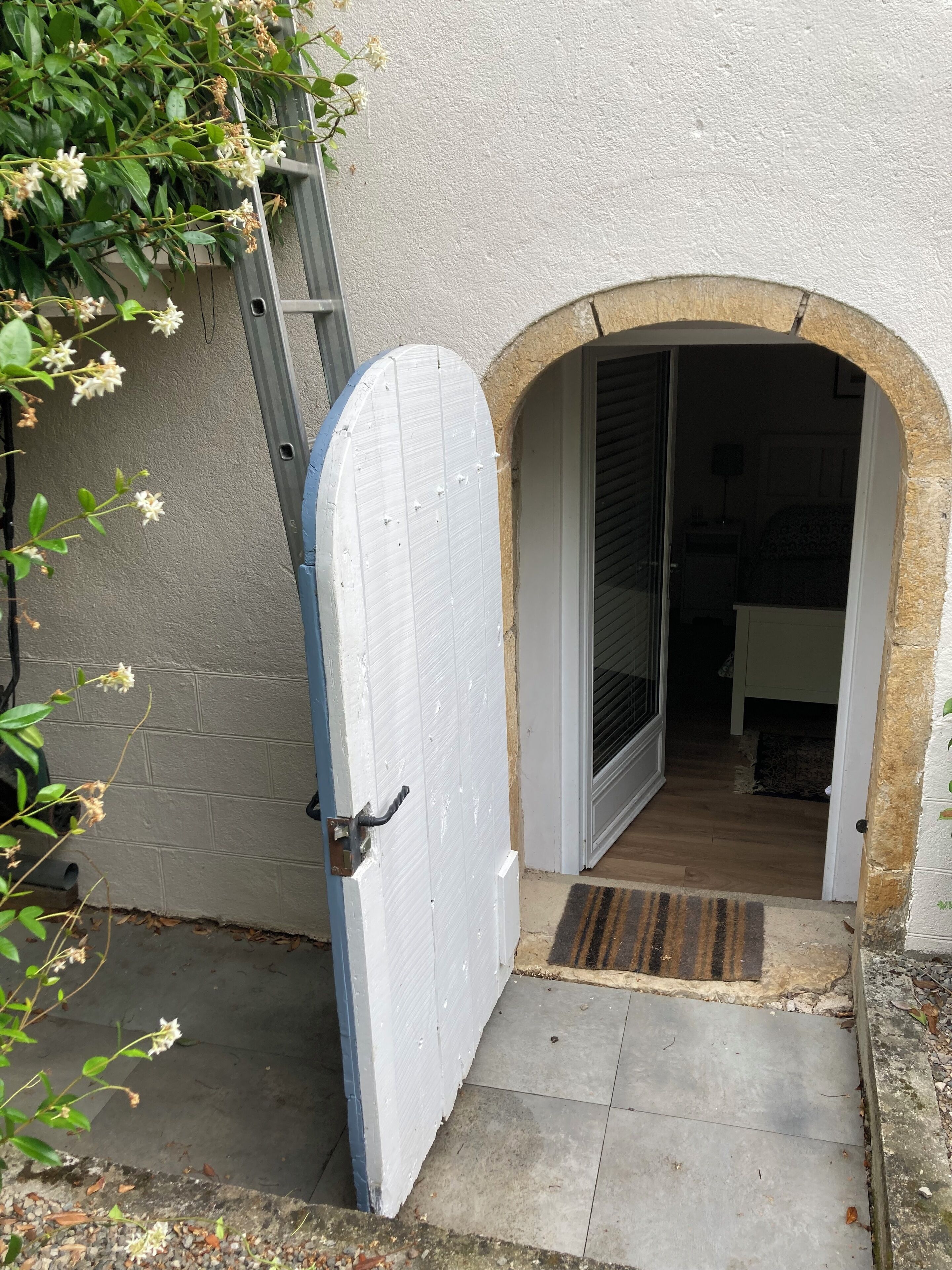 A white door with a metal handle, leading into a room with a wooden floor and a patterned rug.