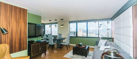 A modern living room with a sofa, chairs, a dining table, and a television.