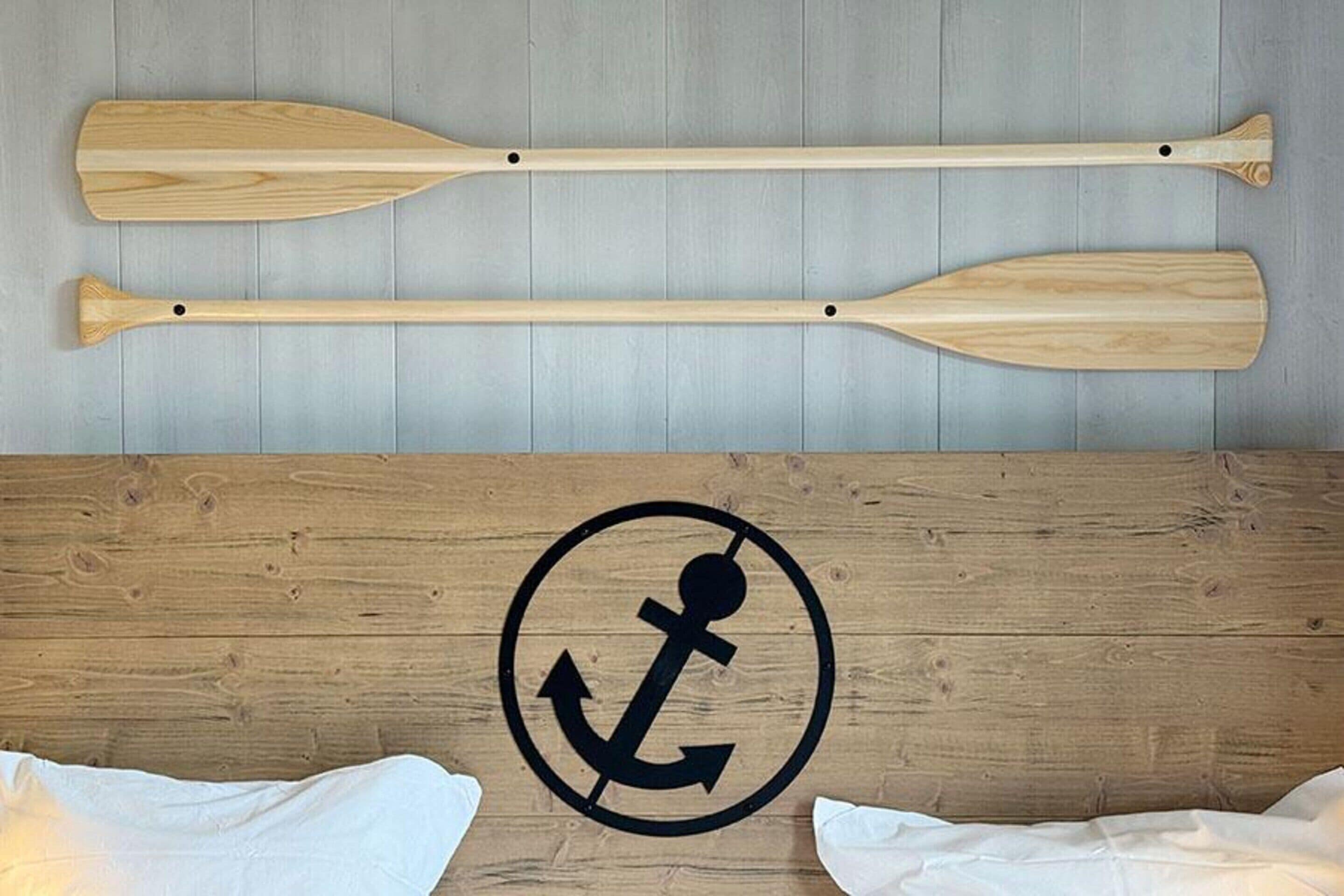 Two wooden paddles and a circular anchor symbol on a wooden wall.
