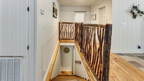 A wooden staircase with a unique railing design, leading to a door with a small decorative plate. - Tranquil Gantt Lake Home w/ Deck & Patio! (Andalusia)