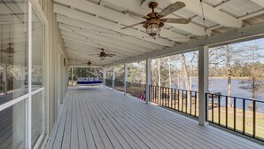 A covered porch with wooden flooring, ceiling fans, and a view of a lake. - Tranquil Gantt Lake Home w/ Deck & Patio! (Andalusia)