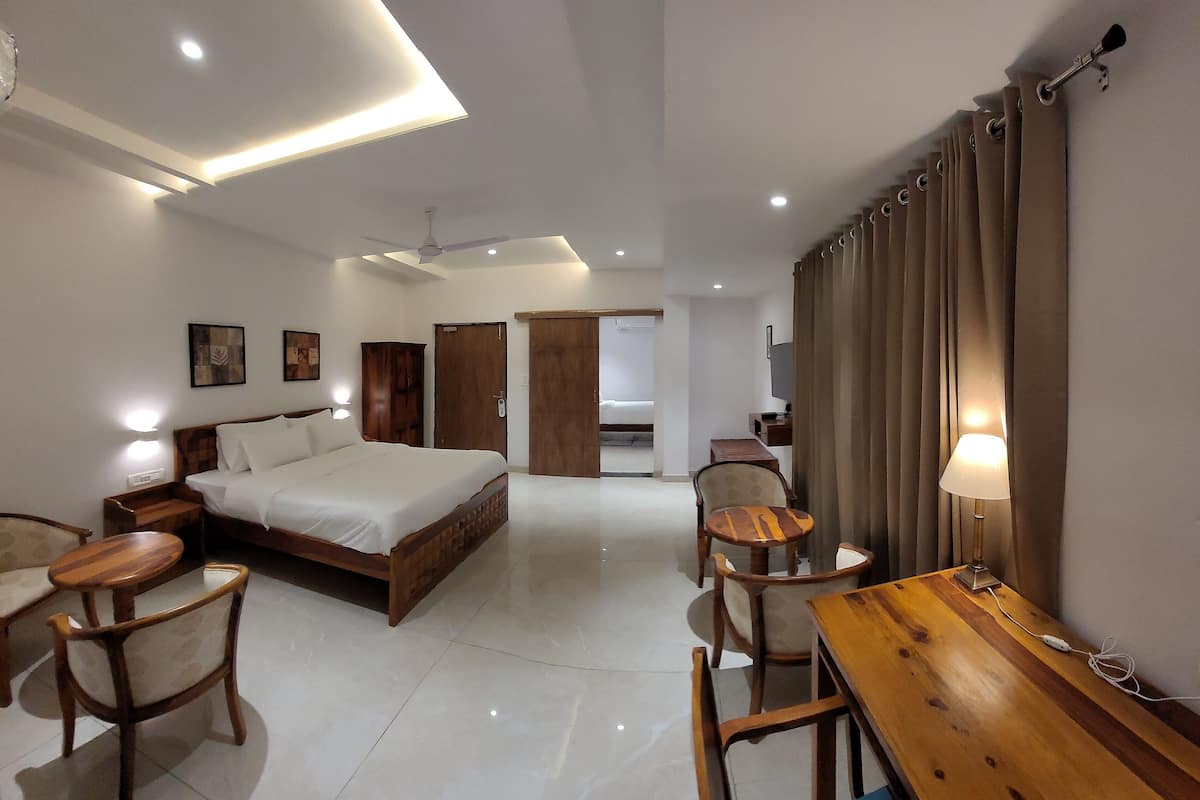 A hotel room with a bed, bedside tables, a desk, chairs, a lamp, and a ceiling fan.