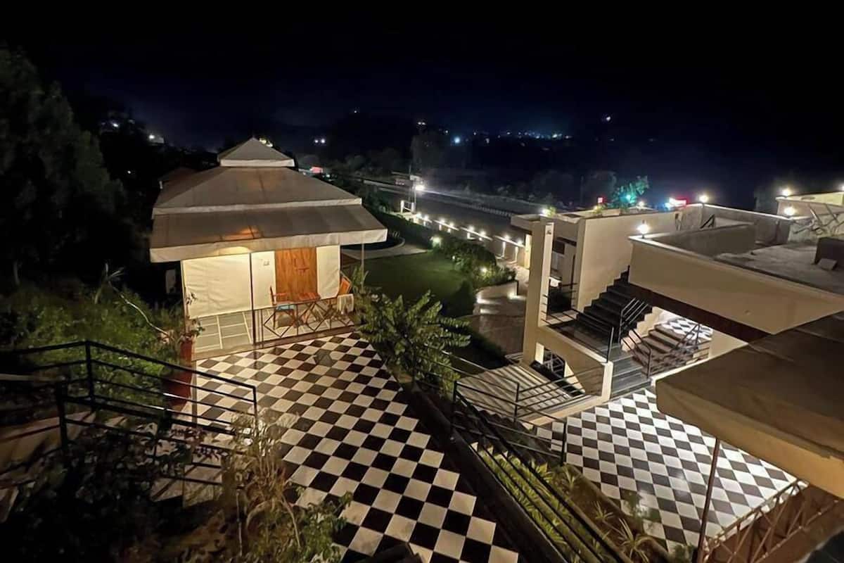 A hotel with a checkered floor, outdoor seating, and a view of the city at night.