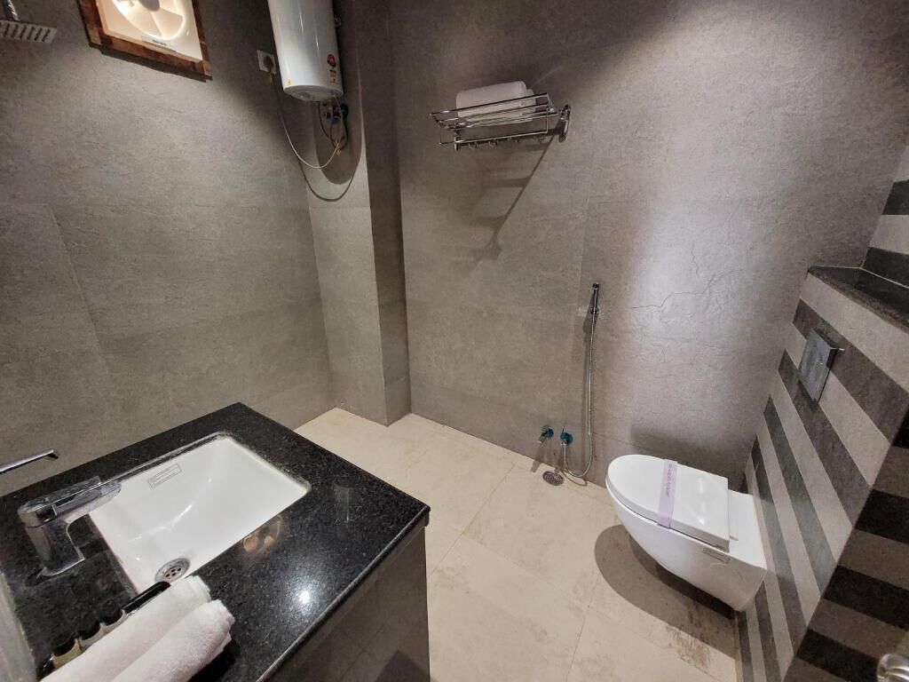 A modern bathroom with a black countertop sink, a white toilet, and a shower area.