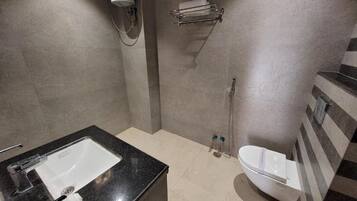 A modern bathroom with a black countertop sink, a white toilet, and a shower area.