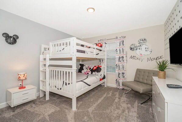 Habitación infantil con literas, escritorio, silla, lámpara y decoración temática de Mickey Mouse.