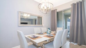 A dining area with a table, chairs, a chandelier, a mirror, and a vase. - Luxurious 4BR Home Pool Near Disney Storey Lake (Kissimmee)