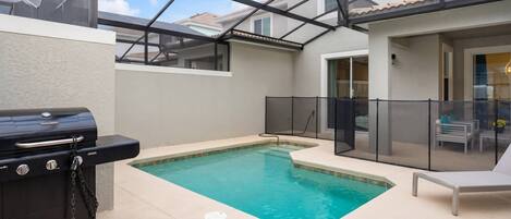 Un patio trasero con piscina, barbacoa y un porche cubierto.
